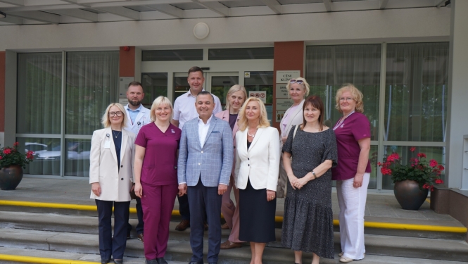 Grupas fotoattēls no reģionālās vizītes pie Cēsu klīnikas ieejas, kurā redzami klīnikas pārstāvji un viesi kopīgā foto uz kāpnēm.