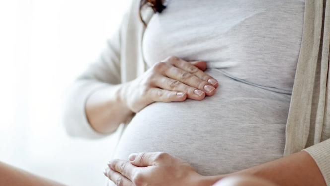 Sieviete gaidībās tur rokas uz vēdera