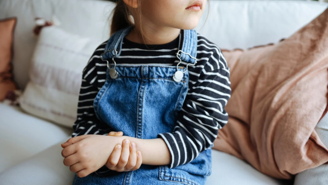 Maza meitenīte tur savu sāpošo roku