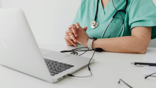 Ārsts sēž pie datora
