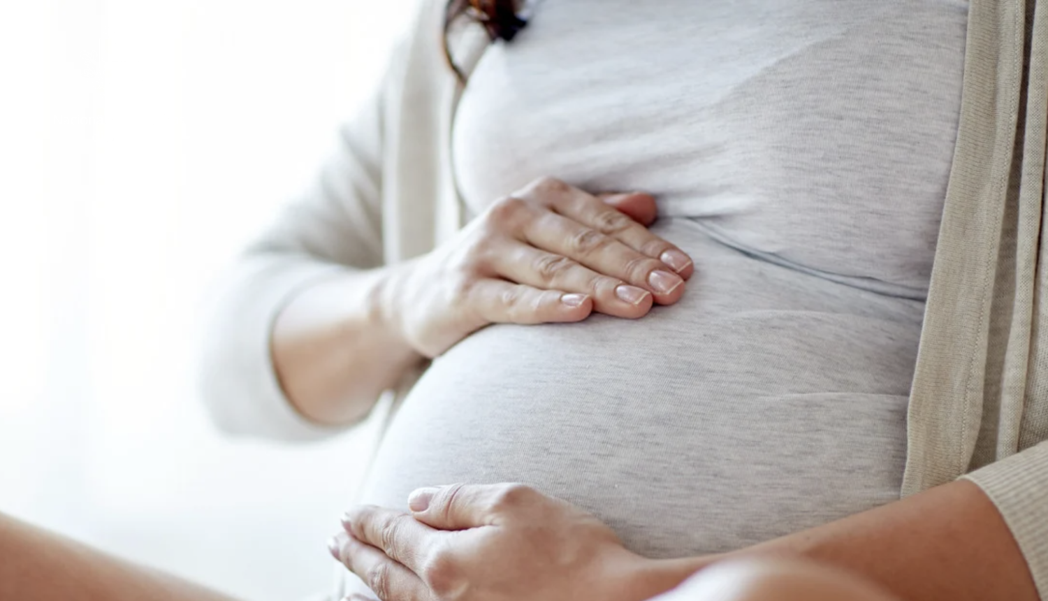 Sieviete gaidībās tur rokas uz vēdera