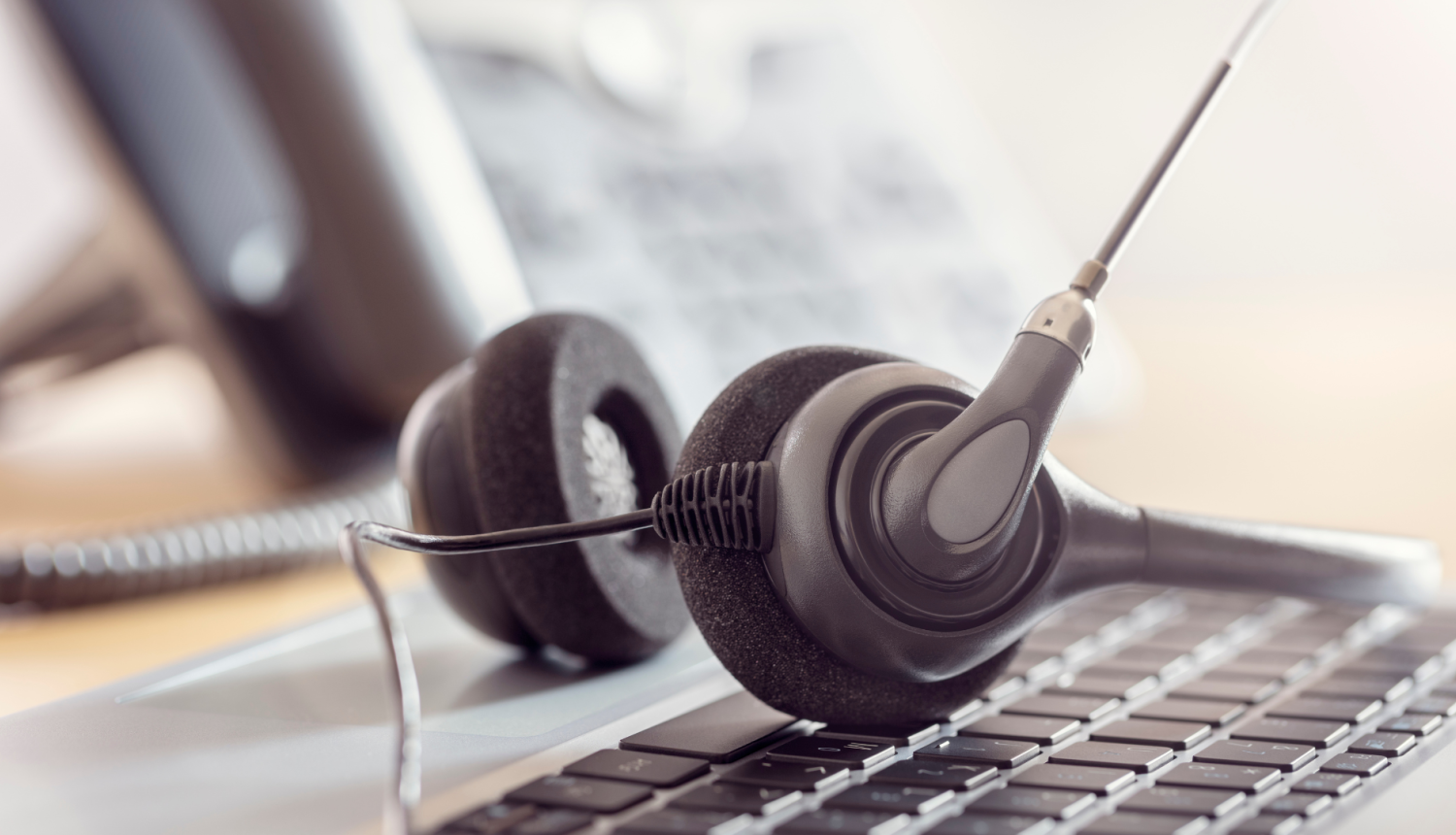 Klientu apkalpošanas centra darba vieta ar austiņām un datoru.